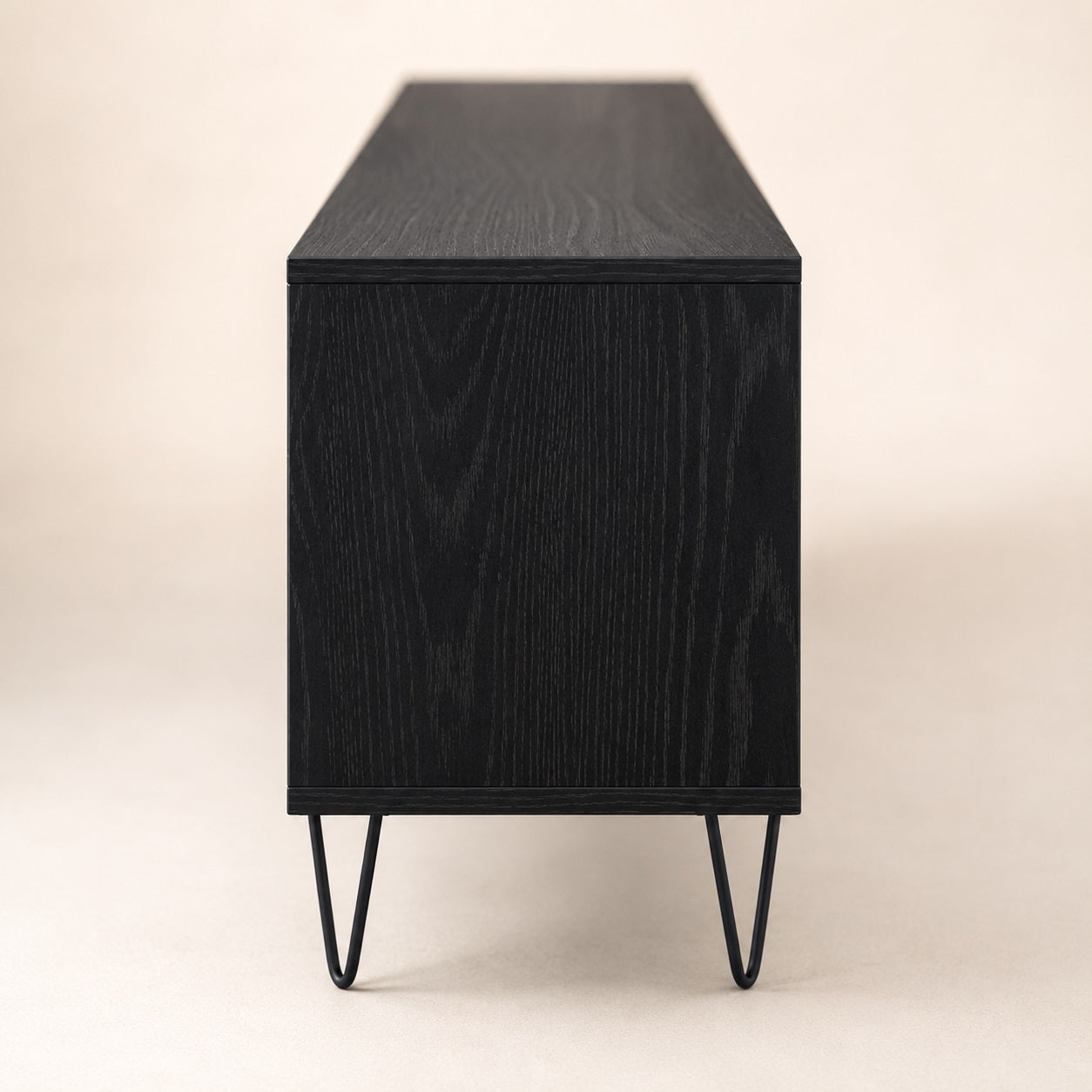 Vue latérale d’un meuble TV moderne noir avec rangement et pieds métalliques