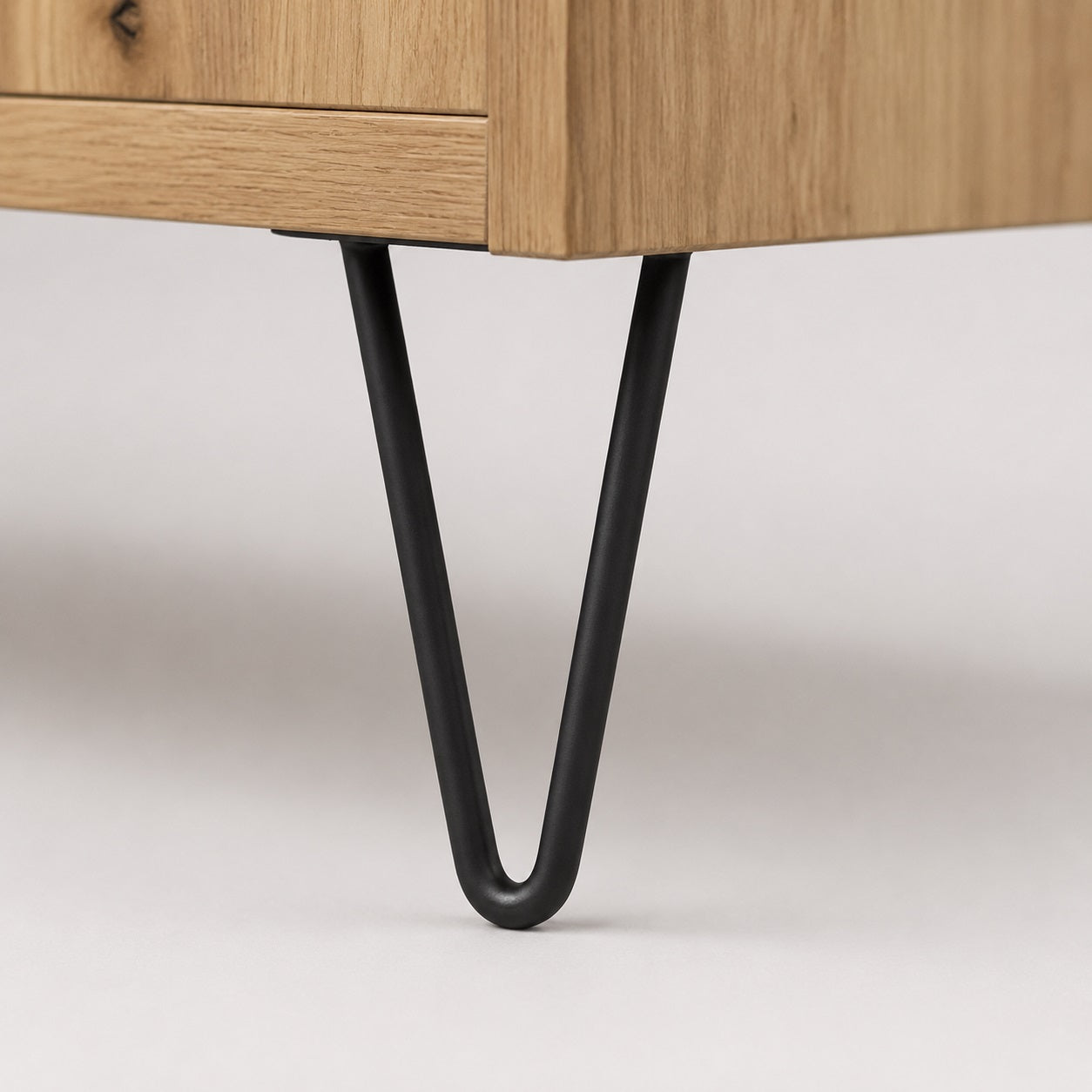 Pied métal noir d’un meuble TV en bois avec rangement, détail du design industriel moderne.