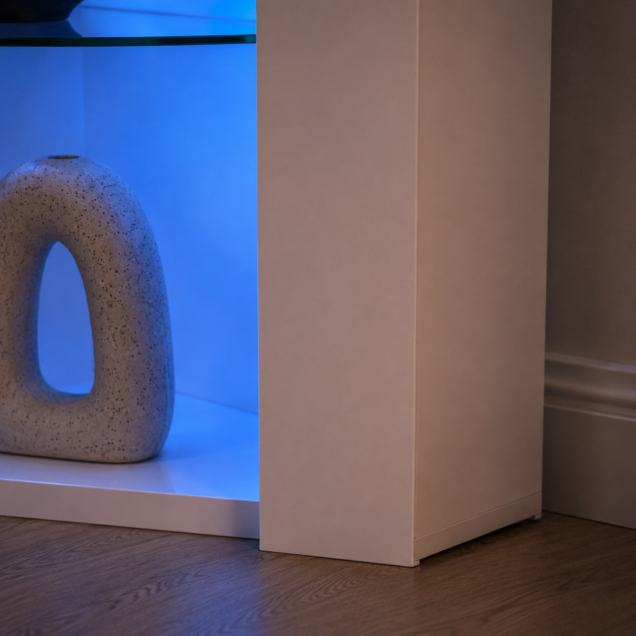 Détail du meuble TV d'angle avec LED intégrées et niche décorative éclairée pour salon moderne.
